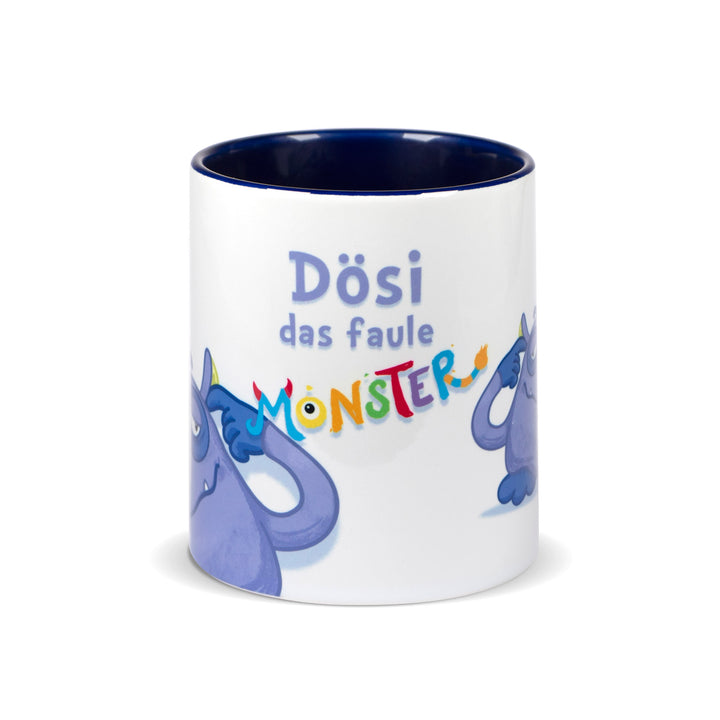 Weiße Keramiktasse mit dunkelblauem Innenrand und der Aufschrift „Dösi das faule Monster“ in bunter, verspielter Schrift.